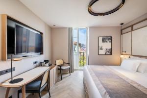 a hotel room with a bed and a desk and a tv at Barceló Funchal Oldtown in Funchal