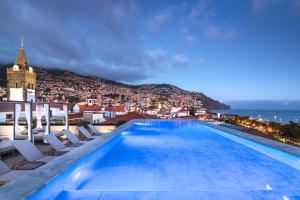 a pool on the roof of a building with chairs at Barceló Funchal Oldtown in Funchal