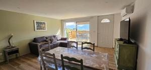 a living room with a dining table and a television at Mini villa T3 climatisée, vue mer, cosy & moderne in Olmeto