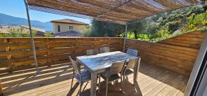 a table and chairs on a wooden deck at Mini villa T3 climatisée, vue mer, cosy & moderne in Olmeto