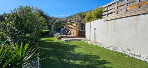 a house with a yard with grass and a building at Mini villa T3 climatisée, vue mer, cosy & moderne in Olmeto