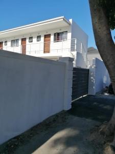 a white house with a white fence and a tree at Mila Lodge 2 in Cape Town
