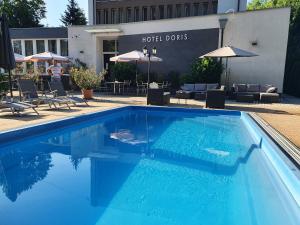 a large blue swimming pool next to a hotel at Doris Hotel in Siófok