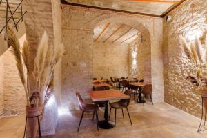 a restaurant with tables and chairs and a stone wall at Palazzo Fontana in Trevi