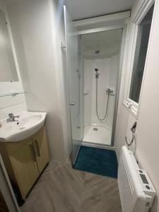 a white bathroom with a shower and a sink at - Mobilhome Camping Les Charmettes - Fun pass non inclus - in Les Mathes