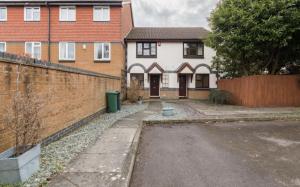 a house with a brick wall and a driveway at Surrey Stays - 2Bed house, 2 parking spaces, RH1, near Gatwick Airport in Redhill