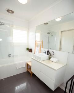 a white bathroom with a tub and a sink at Beachside Getaway Bay Views North Shore VIC Sleeps 12 Free Wifi in North Shore