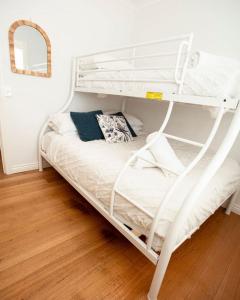 a white bunk bed in a room with a mirror at Beachside Getaway Bay Views North Shore VIC Sleeps 12 Free Wifi in North Shore