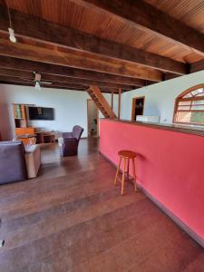uma sala de estar com uma parede vermelha e um banco em Chalés Pico do Caledônia em Nova Friburgo