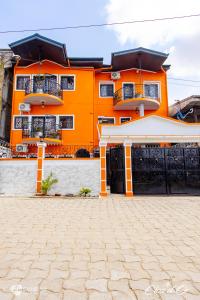 un edificio arancione con due balconi e un vialetto di Clos d'Or, Appartements meublés Douala Makepé a Douala