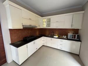 une cuisine avec des placards blancs et un comptoir noir dans l'établissement Guest House DiFi Timoho, à Demangan