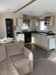 a living room with a couch and a kitchen at Lizard ,Mullion holiday caravan in Mullion