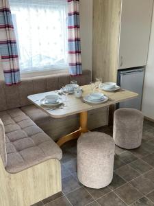 a wooden table with chairs and plates and wine glasses at Lizard ,Mullion holiday caravan in Mullion