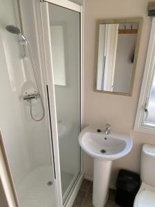 a white bathroom with a sink and a shower at Lizard ,Mullion holiday caravan in Mullion
