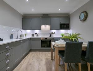 a kitchen with gray cabinets and a wooden table at Durham Riverside Apartments in Durham