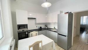 a kitchen with a refrigerator and a table in it at Ernaz Plus Apartments: Promenade Expo in Astana