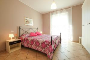 - une chambre avec un lit doté d'oreillers roses et d'une fenêtre dans l'établissement Myconos A6 - Pineto Vacanza, à Pineto