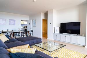 uma sala de estar com um sofá azul e uma televisão em Luxury Beach Front Apartment Moana - Waterviews em Moana