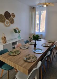 - une table à manger avec des chaises et des assiettes dans l'établissement Appart'hotel SOLESMES, à Solesmes