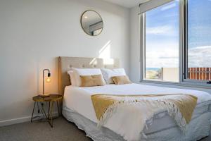 um quarto com uma cama grande e uma janela grande em Luxury Beach Front Apartment Moana - Waterviews em Moana