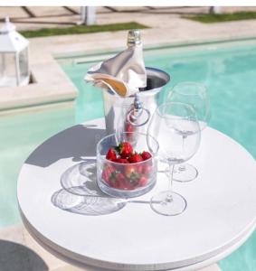 una mesa con un tazón de fresas y copas de vino en B&B VillaSalento LE, en Cavallino di Lecce