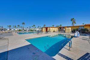 a large swimming pool in a resort with palm trees at Yuma Vacation Rental with Resort Pool and Hot Tub! in Yuma