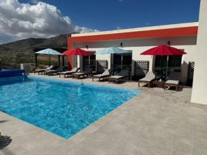 a swimming pool with chairs and umbrellas next to a building at Casa Andmar - Mountain retreat in La Romana