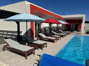 una fila di sedie e ombrelloni accanto alla piscina di Casa Andmar - Mountain retreat a La Romana