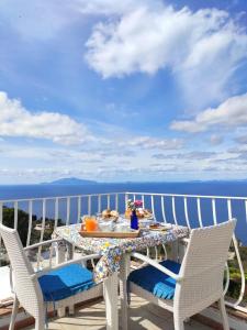 una mesa y sillas en un balcón con vistas al océano en B&B Il Bacio di Capri en Anacapri