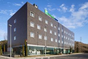 a large brick building with a green sign on it at Holiday Inn Express Pamplona by IHG in Mutilva Baja