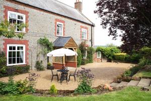 une maison avec une table, des chaises et un parasol dans l'établissement Willow Tree Farm, à Hillington