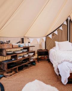 a bedroom in a tent with a bed and a table at Glamping Red Wharf Bay in Pentraeth