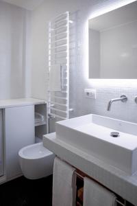 a white bathroom with a sink and a toilet at BasicVillage Milano in Milan