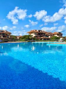 una grande piscina blu con edifici sullo sfondo di Cala Reale Rooms Marinella a Marinella