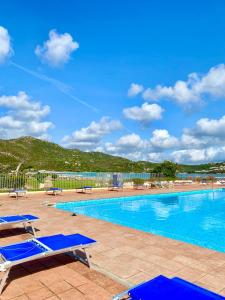 una piscina con due sedie a sdraio blu accanto ad essa di Cala Reale Rooms Marinella a Marinella