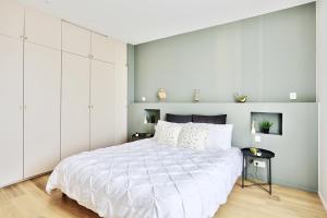 ein Schlafzimmer mit einem großen weißen Bett mit weißen Wänden in der Unterkunft Appartement Le Somptueux - Idéalement Situé in Caluire-et-Cuire