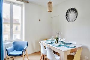 une salle à manger avec une table, des chaises et une horloge dans l'établissement Appartement Le Somptueux - Idéalement Situé, à Caluire-et-Cuire