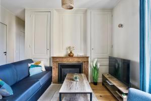 a living room with a blue couch and a fireplace at Appartement Le Somptueux - Idéalement Situé in Caluire-et-Cuire