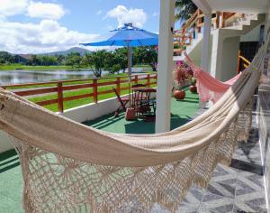 a hammock on a porch with a table and an umbrella at Recanto da Lagoa Flat in Ilha Comprida