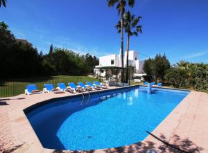 einen großen Pool mit Stühlen und Palmen in der Unterkunft Villa Carvi in Bucht von San Antonio
