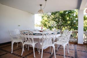a white dining room with white chairs and a table at Villa Carvi in San Antonio Bay