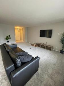 sala de estar con sofá de cuero negro y TV de pantalla plana en Privacy and Exclusivity Condo at Crystal City With Gym en Arlington