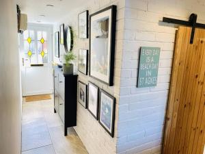 um corredor com uma parede de tijolos brancos com fotografias em Modern Cottage: Free Parking, Garden, Sea Views em St. Agnes