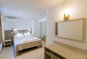 - une chambre d'hôtel avec un lit et un miroir dans l'établissement Résidence Stella di Mare, à Sainte-Lucie de Porto-Vecchio