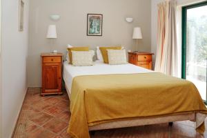 een slaapkamer met een bed met een gele deken erop bij Vila Limão in Boliqueime +29 foto's