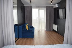 um sofá azul numa sala de estar com cortinas em Дизайнерські апартаменти в ЖК DreamTown 10б em Lutsk