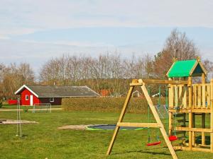 a playground with a wooden swing set in a field at 12 person holiday home in Nordborg in Nordborg