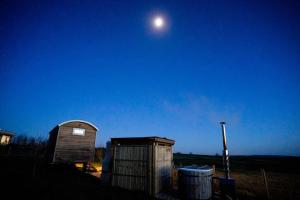 un observatorio y dos cubos de basura en un campo por la noche en Astronomer Shepherd's hut en Beaminster
