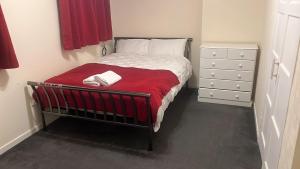 a bedroom with a bed with a red blanket and a dresser at Homie in Aberdeen