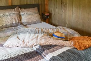 Una cama con una manta y un sombrero. en Landrijk De Reesprong boerderij en Haaksbergen